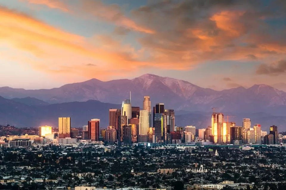 Los Angeles, California skyline against mountains at sunset.